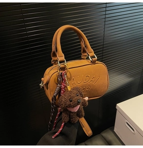 Detailed macro view of the Audai Bear embossed logo on a brown suede Boston bag