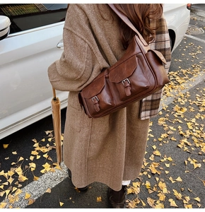 Detail of vintage brown leather crossbody bag featuring dual front flap pockets and side pocket