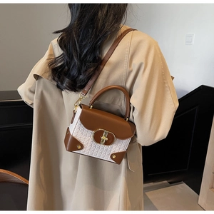 Detail of elegant two-tone crossbody bag with white woven texture and brown leather trim