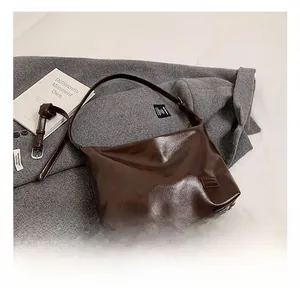 Detail of dark brown glossy PU leather hobo bag with two adjustable shoulder straps
