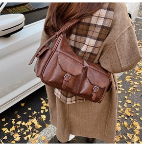 Detail of a vintage dark brown PU leather crossbody bag with dual front pockets