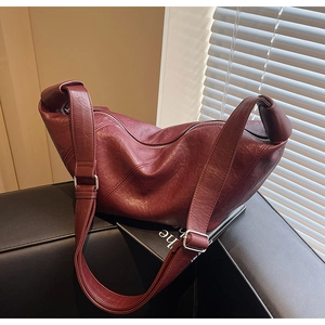 Detail of burgundy textured leather dumpling bag on sofa with soft natural lighting