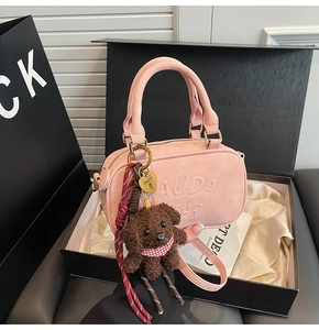 Detail of light pink crossbody bag in a gift box with a brown plush bear charm