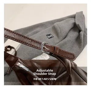 Detail of adjustable shoulder strap with silver buckle on dark brown leather bag