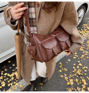 Close-up of vintage brown shoulder bag with multiple pockets and buckled flap detail
