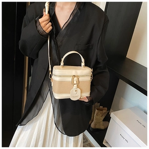 Detail of a beige and khaki bucket bag with textured canvas panels and gold hardware