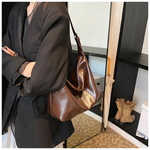 Detailed view of large dark brown hobo shoulder bag in high-gloss faux leather finish