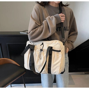 Detail of off-white nylon bucket bag featuring front drawstring pocket and black straps