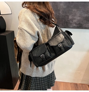 Detail of vintage matte black shoulder bag showing textured leather and front buckle pockets
