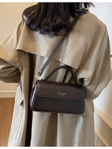 Retro dark brown crossbody bag with top handle worn by a model in a beige trench coat