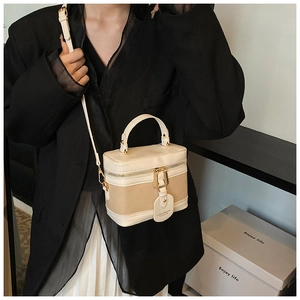 Detail of minimalist bucket bag featuring beige color-blocking and gold dual zippers