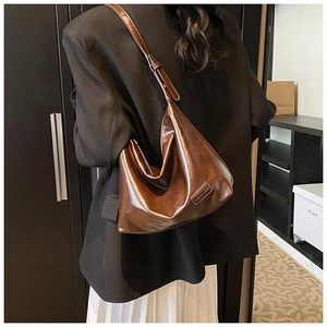 Detailed view of dark brown glossy leather hobo bag with adjustable shoulder strap