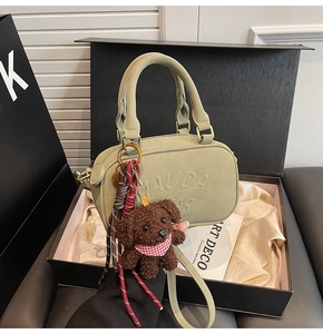 Detailed view of green Boston bag in gift box with teddy bear charm and strap