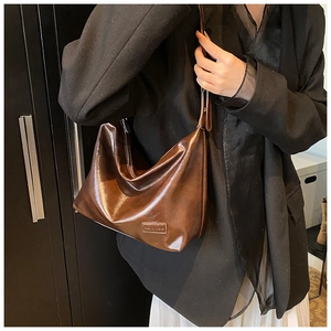 Close-up of vintage glossy dark brown leather shoulder bag with fashion label detail