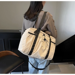 Beige nylon travel tote bag shown on a model for size and capacity visualization