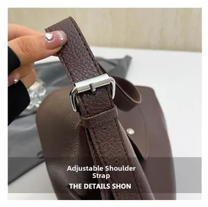 Detail of adjustable shoulder strap with silver metal buckle on dark brown leather bag