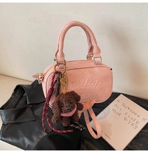 Pink cylinder crossbody bag with plush bear charm and metallic heart detail