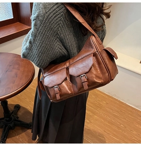Detail of vintage brown shoulder bag with textured faux leather and metal buckle pockets