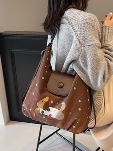 Brown polka dot PU leather crossbody bag with cartoon dog patch in side-view carry