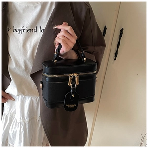 Detail of a vintage black leather vanity bucket bag with gold zippers and a leather handle