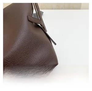 Detail showing the litchi grain texture and stitching on the dark brown leather tote bag