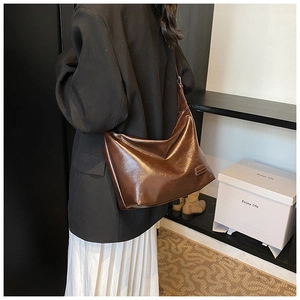 Close-up of a large dark brown glossy leather tote bag with embossed logo detail