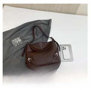 Macro detail of dark brown pebble leather tote bag with metallic buckle and flap design