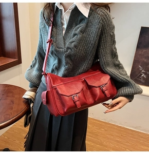 Close-up of a vintage red faux leather crossbody bag with multiple utility pockets
