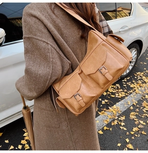 Detail of vintage brown shoulder bag showing dual front pockets with silver metal buckles