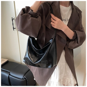 Detail of glossy black hobo bag with sleek leather texture and minimal brand patch