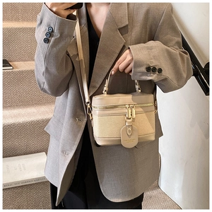 Detail of beige contrast stitch crossbody bag with gold zippers and brand hangtag