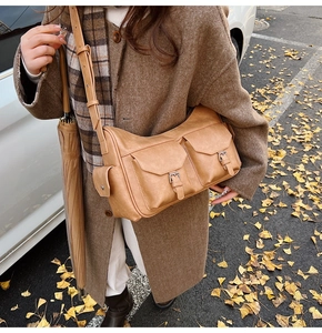 Detail of tan hobo shoulder bag featuring double buckle pockets and adjustable strap