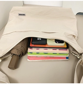 Top view of beige tote bag showcasing large capacity with books and tablet inside