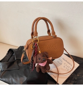 Brown faux leather crossbody bag detail featuring embossed logo and cute puppy pendant