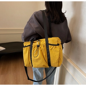 Detailed back view of a yellow nylon crossbody tote bag with black strap and carabiner