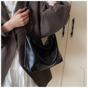 Detail of glossy black leather tote bag showing smooth texture and spacious shoulder strap
