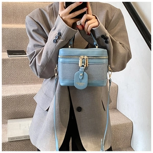 Detail of light blue box-shaped bucket bag with dual zippers and gold hardware