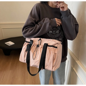 Detail of pink nylon crossbody bag with black wide straps and metal buckle