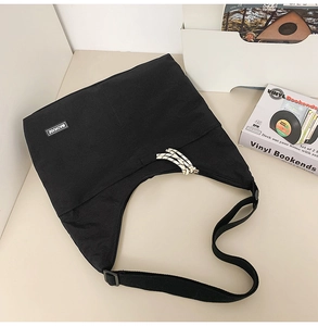 Detail view of large black canvas crossbody bag with woven drawstring zipper and logo tag