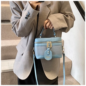 Detail of light blue box bag showing leather fabric stitch and golden zipper closure