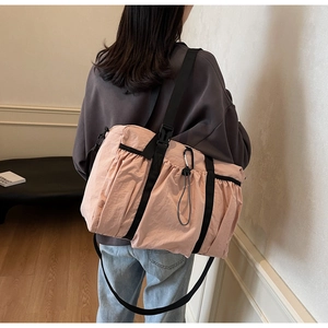 Detail of pink nylon bucket bag with pleats and black adjustable shoulder strap