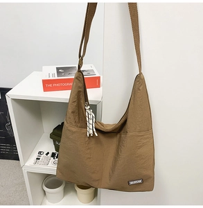 Close-up of brown nylon tote with brand logo and striped rope zipper detail