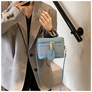Detail view of the two-tone bucket bag with dual zippers and leather handle on a model