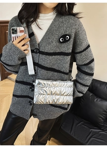 Close-up of quilted metallic silver puffer bag featuring a wide white woven shoulder strap