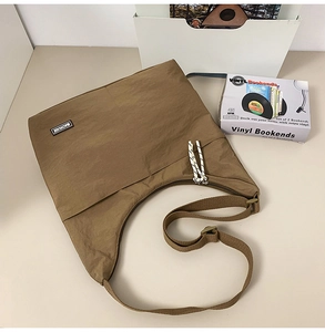 Detail of brown waterproof nylon crossbody bag with black brand logo and woven zipper