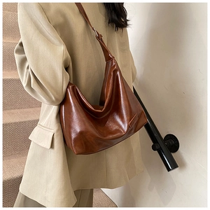 Brown semi-moon shoulder bag in glossy leather shown as a stylish lifestyle outfit detail