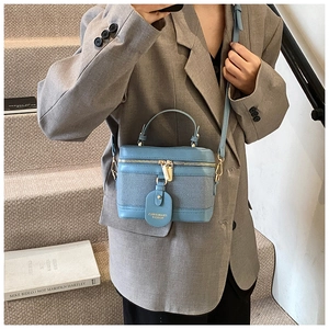 Close-up of blue patchwork bucket bag with textured fabric and golden zipper