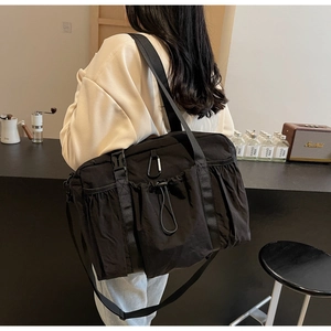 Back view of model carrying a large black casual bucket bag with multi-pocket details