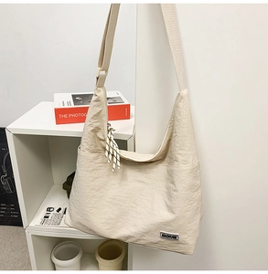 Detail of off-white nylon hobo bag featuring a woven strap and contrast logo patch