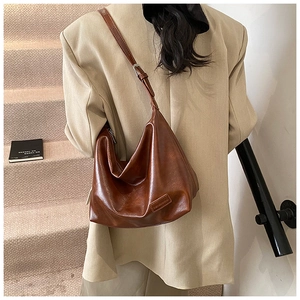 Close-up of brown vintage leather tote bag with pleated texture and adjustable strap